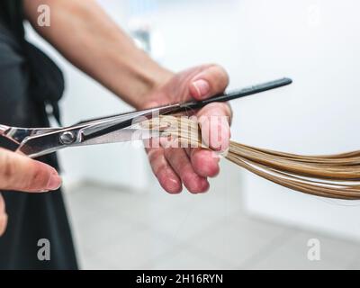 Ritagliare un parrucchiere irriconoscibile utilizzando le forbici per tagliare i capelli giusti del cliente nel salone di bellezza Foto Stock