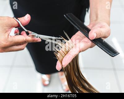 Ritagliare un parrucchiere irriconoscibile utilizzando le forbici per tagliare i capelli giusti del cliente nel salone di bellezza Foto Stock