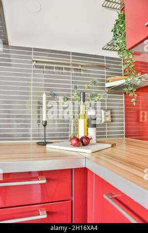 Bottiglia di olio e sale posta sul bancone rosso con candela e fiori in cucina moderna Foto Stock
