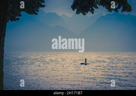 Disegno acquerello di vista delle Alpi di montagna, figura silhouette di un uomo su una tavola da surf con pagaia sul lago Leman Lago di Ginevra a Montreux, R svizzero Foto Stock