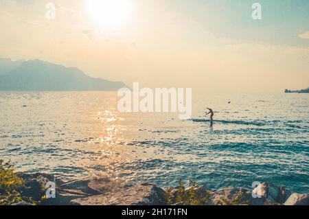 Disegno acquerello di vista delle Alpi di montagna, figura silhouette di un uomo su una tavola da surf con pagaia sul lago Leman Lago di Ginevra a Montreux, R svizzero Foto Stock