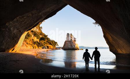 Due persone godono della vista della Cove Cattedrale all'alba, Penisola Coromandel, Isola del Nord, Nuova Zelanda Foto Stock