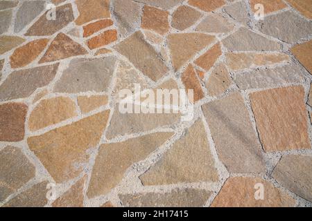 Superficie stradale arancione in pietra. Trama senza giunture. La tessitura di una strada di pietra. Foto di alta qualità Foto Stock