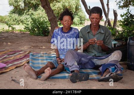 Un vecchio boscimano di Kalahari centrale, villaggio New Xade in Botswana, di fronte al suo cortile seduto con la moglie Foto Stock