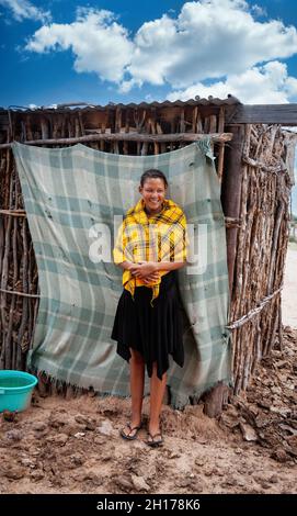 Una giovane ragazza bushman di Kalahari centrale, villaggio New Xade in Botswana, di fronte al suo capanno Foto Stock