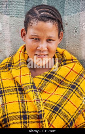 giovane basarwa con trecce e coperta gialla Foto Stock