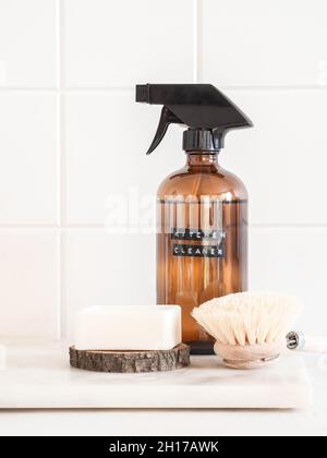 Concetto di pulizia della casa senza rifiuti. Flacone ambrato con soluzione di lavaggio, spazzola e sapone su ripiano in marmo. Vari articoli e ingredienti per la casa ecologica Foto Stock