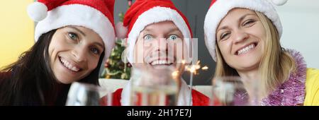 Uomo e donna in babbo natale cappelli bere champagne e tenere scintille nelle loro mani Foto Stock