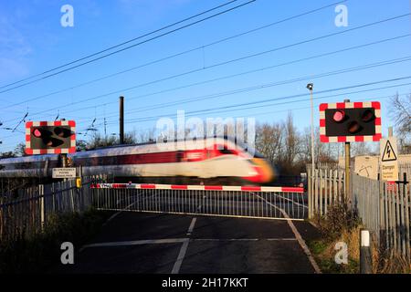 Treno Azuma che passa luci rosse a un incrocio senza equipaggio, East Coast Main Line Railway, Peterborough, Cambridgeshire, Inghilterra, Regno Unito Foto Stock