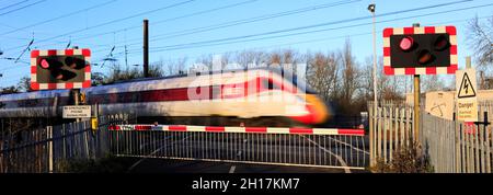 Treno Azuma che passa luci rosse a un incrocio senza equipaggio, East Coast Main Line Railway, Peterborough, Cambridgeshire, Inghilterra, Regno Unito Foto Stock