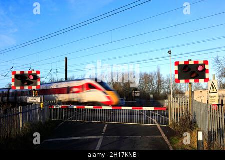 Treno Azuma che passa luci rosse a un incrocio senza equipaggio, East Coast Main Line Railway, Peterborough, Cambridgeshire, Inghilterra, Regno Unito Foto Stock