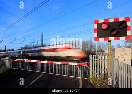 Treno Azuma che passa luci rosse a un incrocio senza equipaggio, East Coast Main Line Railway, Peterborough, Cambridgeshire, Inghilterra, Regno Unito Foto Stock