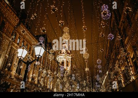 Lanterna ardente e luci dorate della città di notte in decorazioni natalizie festive. Natale glowing ghirlande d'oro sulla strada di Mosca sera. Foto Stock