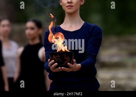 Olympia, Grecia. 17 ottobre 2021. Un esecutore tiene una ciotola di fiamma olimpica durante la prova di vestito per l'illuminazione della fiamma olimpica nell'antica Olimpia, il luogo di nascita degli antichi Giochi Olimpici. La fiamma sarà trasportata da un relè di torcia a Pechino, in Cina, dove si terranno le Olimpiadi invernali dal 4 al 20 febbraio 2022. Credit: Angelos Tzortzinis/dpa/Alamy Live News Foto Stock