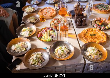 Concetto di cibo, tavolo con vari spuntini disposti su di esso. Insalata con salmone, caesar skuric, funghi sottaceto, pane Foto Stock