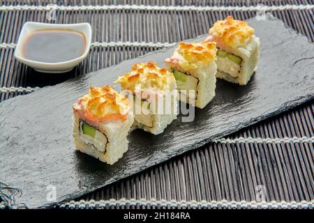 Rotoli di cetrioli cotti al forno su una pietra scura. Sushi giapponese. Foto Stock