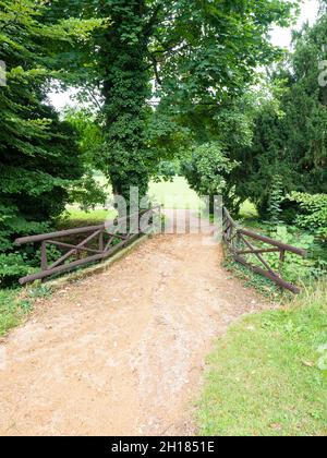 Il sentiero nel parco del castello conduce su un ponte di pietra. Mattinata estiva dopo la pioggia. Foto Stock