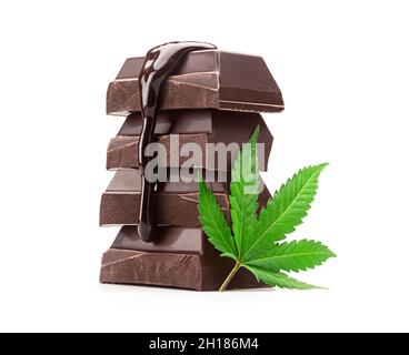 Pila di pezzi della barra di cottura al cioccolato scuro con salsa di cioccolato fusa che si versa sopra e foglia di Cannabis isolato su sfondo bianco Foto Stock