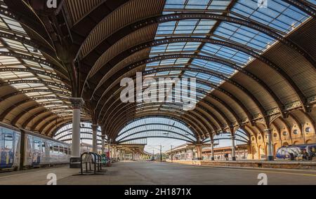 Un panorama di un atrio della stazione ferroviaria. Una tettoia di ferro del 19 ° secolo con un lucernario è sopra le piattaforme dove un treno aspetta. Foto Stock