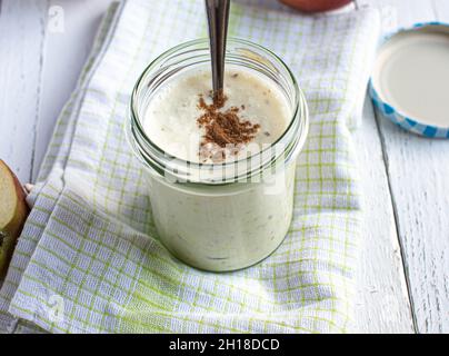 Yogurt fatto in casa con mela rossa purea e condimento alla cannella servito su sfondo bianco con cucchiaio. Foto Stock