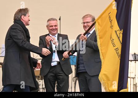 17 ottobre 2021, Baden-Wuerttemberg, Überlingen am Bodensee: Joachim Schuster (r), sindaco di Neuenburg am Rhein, detiene la bandiera dello spettacolo orticolo di Stato, che ha ricevuto da Manne Lucha (Bündnis90/Die Grünen, l), ministro dell'integrazione e degli Affari sociali a Baden-Württemberg, durante una cerimonia di fronte a centinaia di visitatori. L'anno prossimo, nel 2022, Neuenburg am Rhein ospiterà lo state Garden Show. In tale contesto è Gerhard Hugenschmidt (centro), presidente dell'assemblea degli azionisti della Förderungsgesellschaft für die Baden-Württembergischen Landesgartenschauen mbH. Foto: Feli Foto Stock