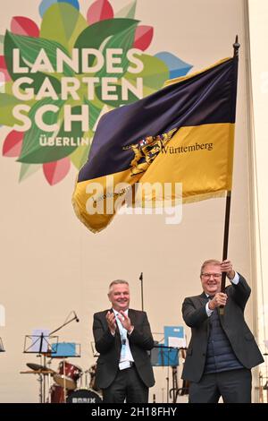 17 ottobre 2021, Baden-Wuerttemberg, Überlingen am Bodensee: Joachim Schuster (r), sindaco di Neuenburg am Rhein, detiene la bandiera dello spettacolo orticolo di Stato, con cui è stato presentato durante una cerimonia di fronte a centinaia di visitatori. L'anno prossimo, nel 2022, Neuenburg am Rhein ospiterà lo state Garden Show. In tale contesto è Gerhard Hugenschmidt (l), presidente dell'assemblea degli azionisti della Förderungsgesellschaft für die Baden-Württembergischen Landesgartenschauen mbH. Foto: Felix Kästle/dpa Foto Stock