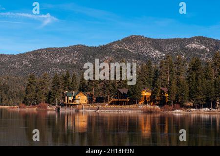 Le case e gli alberi sempreverdi si riflettono sul lago Big Bear. Big Bear Lake, California, Stati Uniti. Foto Stock