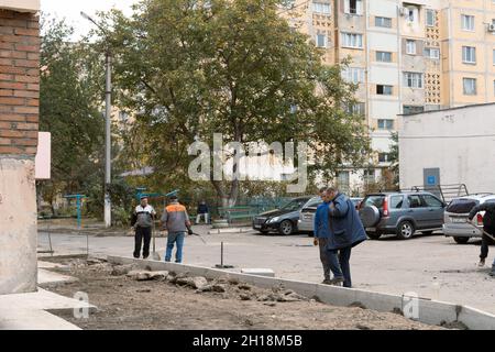 Tiraspol, Moldavia - 15 ottobre 2021: I lavoratori dei servizi stradali installano nuovi cordoli di cemento nel cortile di un edificio di appartamenti nella capitale del Foto Stock