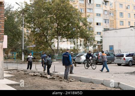 Tiraspol, Moldavia - 15 ottobre 2021: I lavoratori dei servizi stradali installano nuovi cordoli di cemento nel cortile di un edificio di appartamenti nella capitale del Foto Stock
