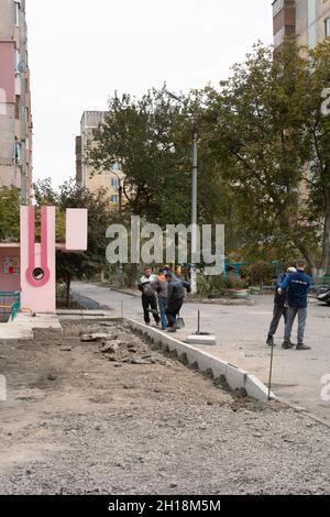 Tiraspol, Moldavia - 15 ottobre 2021: I lavoratori dei servizi stradali installano nuovi cordoli di cemento nel cortile di un edificio di appartamenti nella capitale del Foto Stock