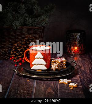 Cioccolata calda fatta in casa o caffè in un rustico abbraccio rosso con biscotti di Natale di Gingerbread su un piatto come accogliente delizia invernale. Foto Stock