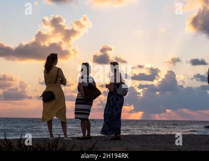 I turisti guardare il sole che tramonta al porto di Paphos, Cipro. Foto Stock