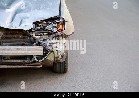 Cofano rotto di auto su strada dopo un incidente con nessuno copyspace. Macchina rotta rifiuti mucchio spazzatura. Fari del paraurti e dell'auto rotti con la spia accesa Foto Stock