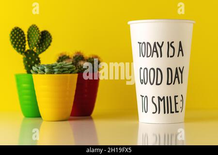 Cactus in pentola con una tazza di carta di caffè su scrivania in legno. Concetto minimo di buon giorno. Foto Stock