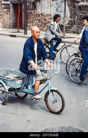 Un uomo cinese che guida il suo triciclo di carico sulla strada a Beiing, Cina. Foto Stock