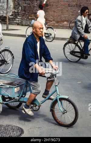 Un uomo cinese che guida il suo triciclo di carico sulla strada a Beiing, Cina. Foto Stock