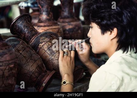 Un artigiano attacca i cloison o la striscia di filo per fare il disegno per un vaso di cloissone in un laboratorio a Pechino, Cina. Foto Stock