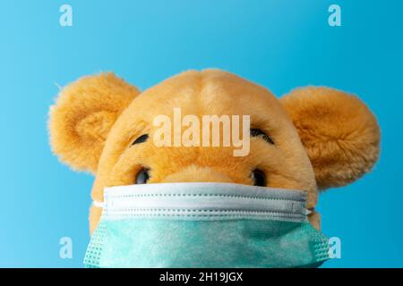Composizione creativa con orso giallo con maschera virus. Epidemia minima di virus Corona. Concetto di vacanza. Foto Stock
