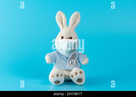 Composizione creativa con simpatica bambola conigliata con maschera virus. Epidemia minima di virus Corona. Concetto di vacanza. Foto Stock