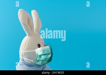 Composizione creativa con simpatica bambola conigliata con maschera virus. Epidemia minima di virus Corona. Concetto di vacanza. Foto Stock