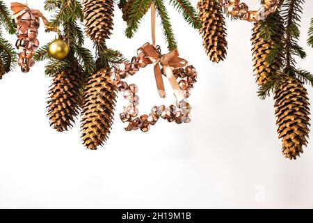 Cornice di Natale di rami di albero su sfondo bianco con spazio copia. Carta festiva con ramo di abete con coni di pino e giocattoli da campane rosa e. Foto Stock