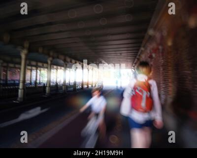 Vista posteriore di una donna irriconoscibile che cammina sotto il ponte olandese con una silhouette sfocata Foto Stock