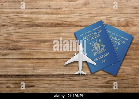 Due passaporto ugandese e modello di aeroplano su una tavola di legno Foto Stock