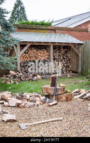 Pali di legno con legna da ardere tagliata fuori da un deposito di tronchi in un giardino del Regno Unito. Rappresenta il concetto di energia rinnovabile, biomassa e biocarburante Foto Stock