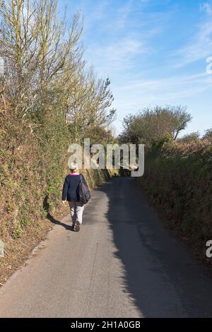 dh Country Lane STRADE GUERNSEY Donna turistica che cammina giù campagna strada escursionista persone Foto Stock