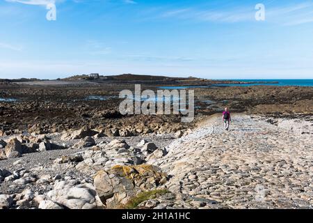 dh LIHOU ISOLA GUERNSEY Donna turista a piedi sulla strada rialzata per le isole Foto Stock