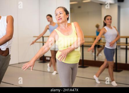 Ritratto di donna matura praticando danza balletto si muove durante la classe di gruppo in studio coreografico Foto Stock