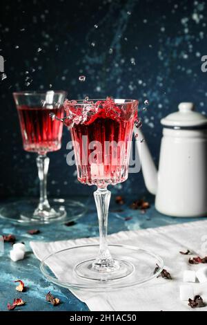 Bicchiere di tè rosso caldo con spruzzi sul tavolo Foto Stock