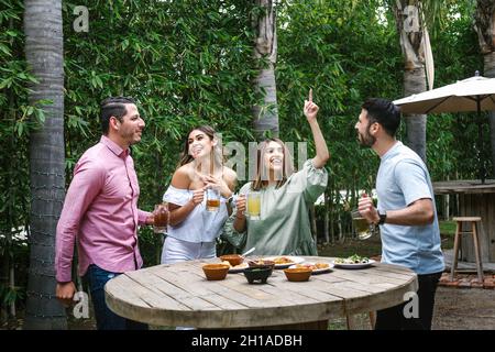 Gruppo di giovani amici latini incontro per birra, bevande michelada e cibo messicano preparare un toast nella terrazza del ristorante in Messico America Latina Foto Stock