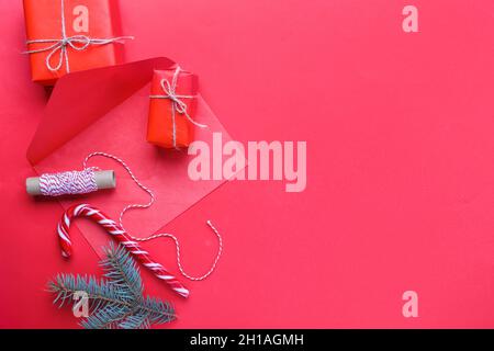 Busta con decorazioni natalizie e scatole regalo su sfondo rosso Foto Stock